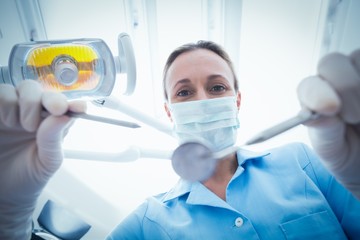 Fototapeta premium Female dentist in surgical mask holding dental tools