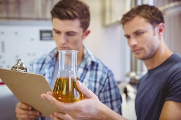 Two men looking at the beaker with beer