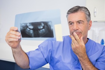 Thoughtful dentist studying x-ray attentively