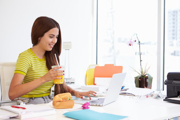 Woman Working In Design Studio Having Lunch At Desk