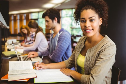 Student looking at camera while studying with classmates