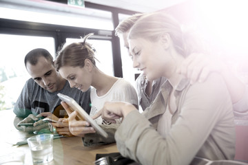 Obraz premium Group of friends in campus lounge websurfing with tablet