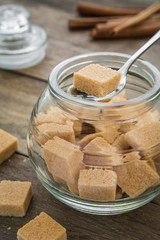 Brown sugar cubes in spoon on jar