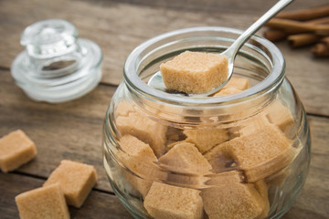 Brown sugar cubes in spoon on jar
