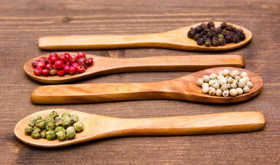 Wooden spoons with mixed peppers on wooden table