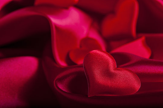 red heart Valentine's Day symbols on red silk background