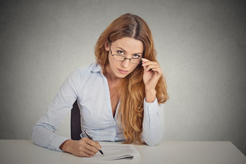 businesswoman with glasses sitting at desk looking at you 