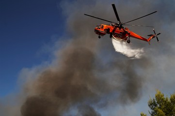 Fototapeta na wymiar Firefigthers are fighting with bushfire. Helicopter drops water from the sea
