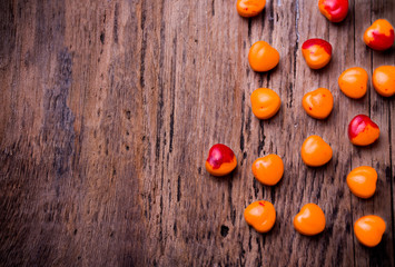 Fototapeta na wymiar Orange, red heart shaped pills or candy on vintage wooden