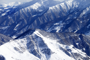 Top view on snowy mountains with forest