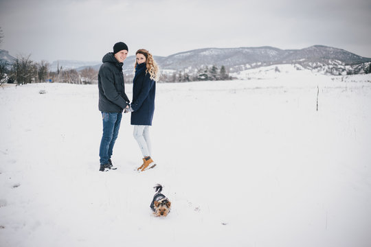 Young couple having a walk with their dog in snowy countryside