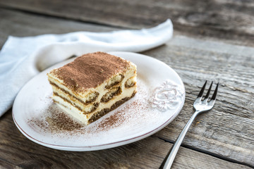 Tiramisu in the plate on the wooden background
