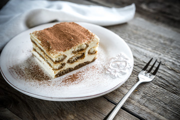Tiramisu in the plate on the wooden background