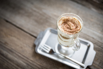 Tiramisu in the glass on the wooden background