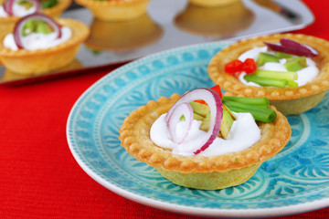 Tartlets with greens and vegetables with sauce on plate and