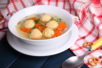 Soup with meatballs and noodles in bowl on wooden background