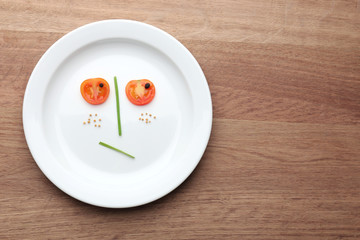 Vegetable face on plate on wooden table