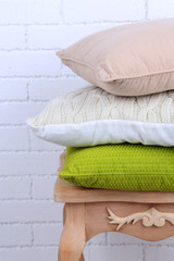 Pillows on small wooden table and white brick wall background