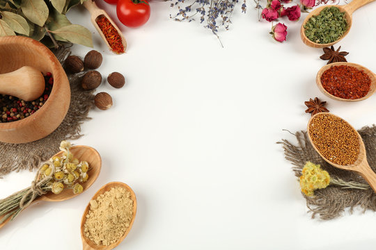 Different spices and herbs in wooden spoons isolated on white