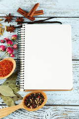 Spices with recipe book on color wooden table background