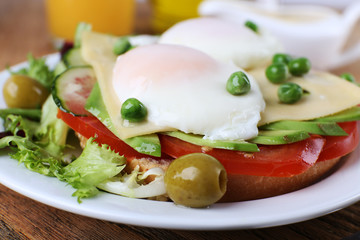 Fototapeta na wymiar Sandwich with poached eggs, cheese and vegetables