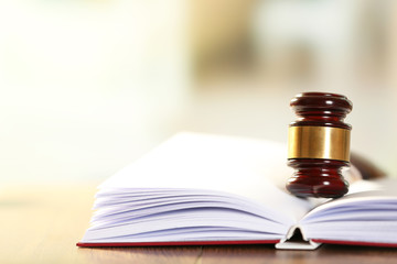 Wooden judges gavel lying on law book, close up