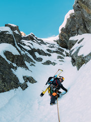 Ice climbing: mountaineer on a mixed route of snow and rock duri