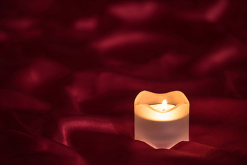 Candle on the red cloth background