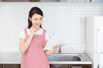 タブレットを見ながら料理をする女性 