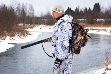 Naklejka premium hunter with gun on the river bank