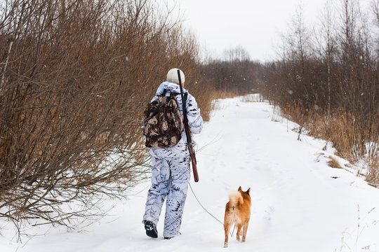 hunter with his dog walking on the winter road