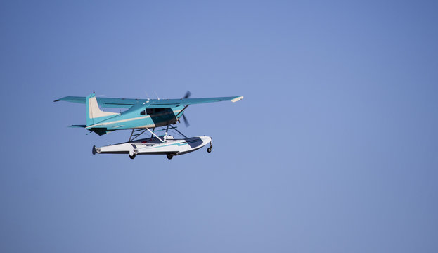 Turquoise sea plane taking off against blue sky