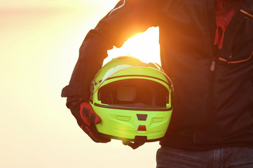 biker man helmet in hand sunset - 76137577