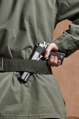Soldier in uniform holding gun in his belt