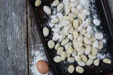Gnocchi on Cookie Sheet and Rustic Wooden Background