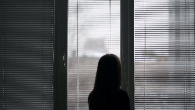 girl closes the window blinds