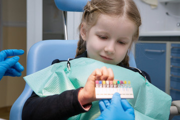 the child dental picks colored fillings on clinic