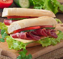 Big sandwich with raw smoked meat on a wooden background