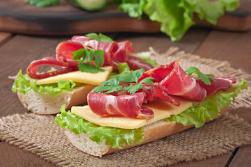 Big sandwich with raw smoked meat on a wooden background