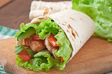 Fresh tortilla wraps with chicken nuggets and vegetables on plat