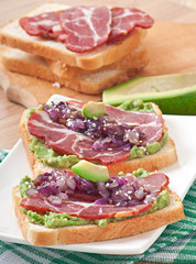 Sandwich with ham, avocado sauce and caramelized onions