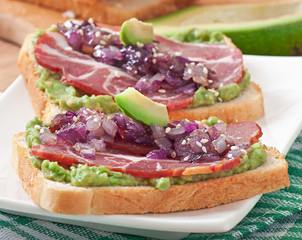 Sandwich with ham, avocado sauce and caramelized onions