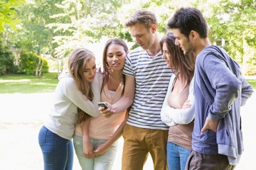Happy students looking at smartphone outside on campus