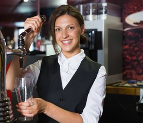 Happy barmaid pulling a pint of beer