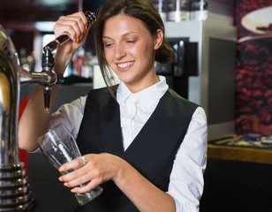 Happy barmaid pulling a pint of beer