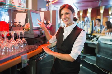 Happy barmaid using touchscreen till