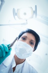 Fototapeta na wymiar Female dentist in surgical mask holding dental drill