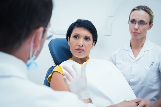 Male dentist with assistant examining womans teeth