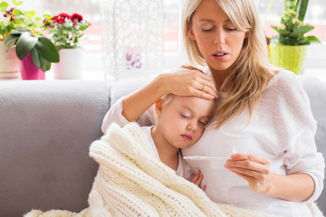 Mother checking temperature of her sick child - Powered by Adobe