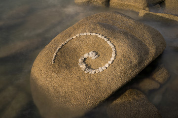 Fototapeta na wymiar Esoterische Spirale aus Granitsteinen auf Felsen